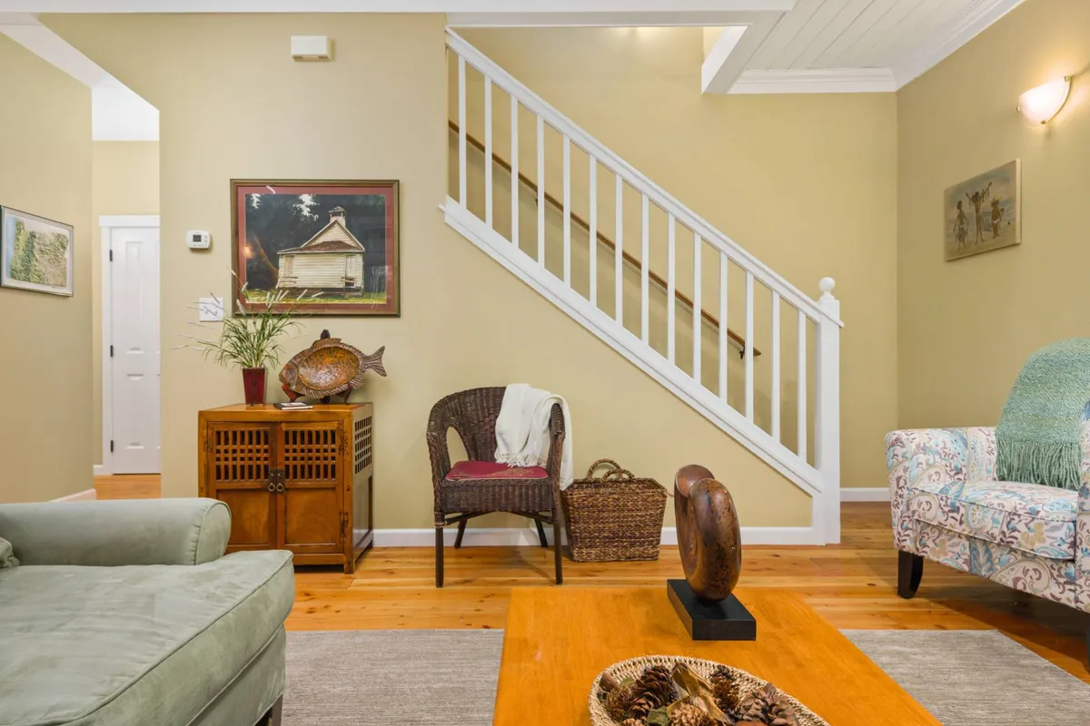 An enticing view of a staircase leading to the upstairs bedrooms, framed by tasteful artwork and a comfortable seating arrangement. The image bridges the communal main floor and the private upstairs quarters, visually narrating the transition from shared activity to restful retreat.