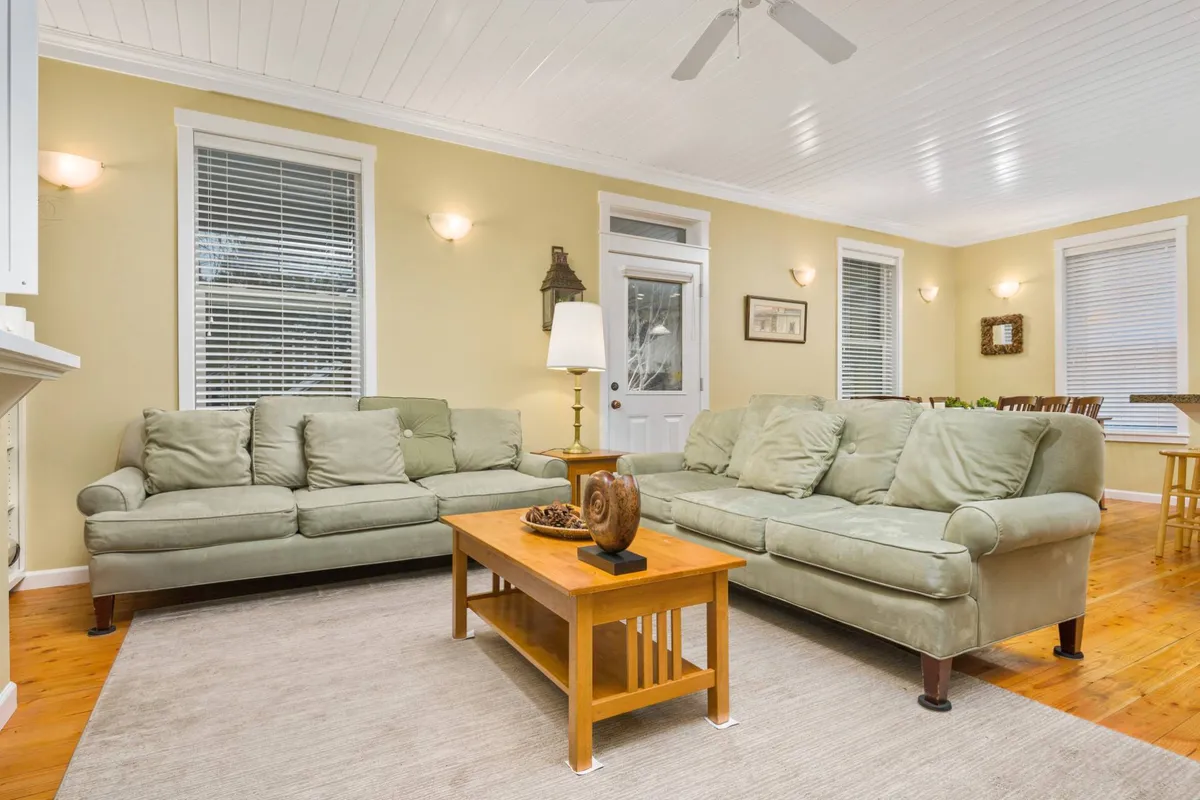 A cozy living room with plush sofas and a coffee table arranged for relaxation or gathering, softly illuminated by a table lamp. The space feels intimate and inviting, ideal for group activities like board games or storytelling.
