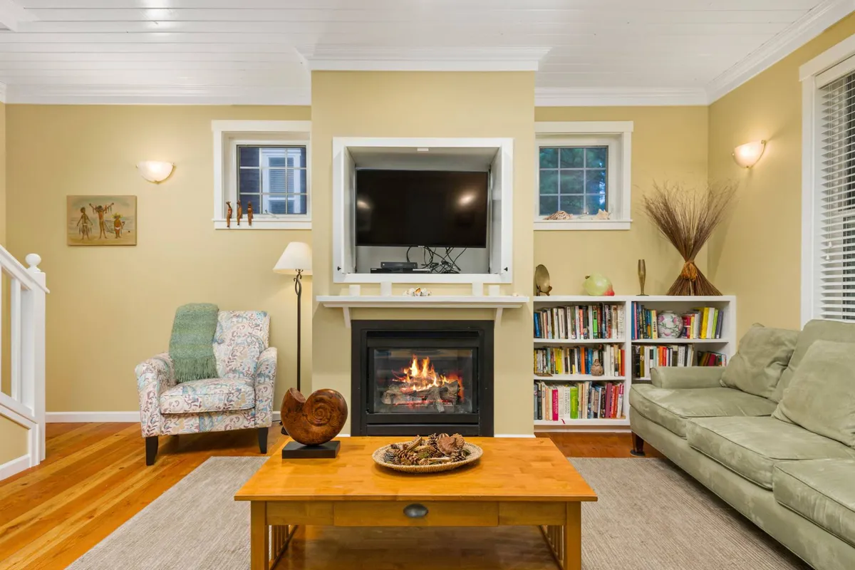 A warm, inviting living area with a comfortable sofa, a glowing fireplace as the focal point, a coffee table, and a bookshelf. The arrangement is both spacious and cozy, ideal for gathering, relaxing, or enjoying quiet moments, and suggestive of a welcoming environment for all guests, including those with mobility needs.